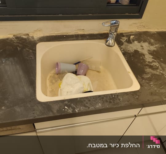משטח שיש כהה וכיור מותקן במטבח במהלך עבודות התקנה